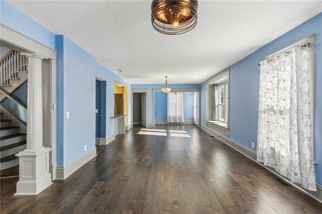 spare room with decorative columns and dark wood-type flooring