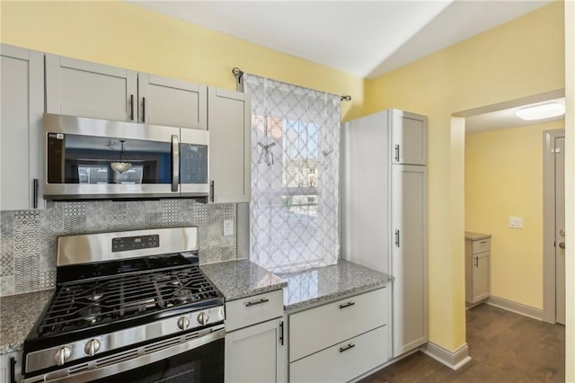 kitchen featuring light stone countertops, dark hardwood / wood-style flooring, stainless steel appliances, and tasteful backsplash