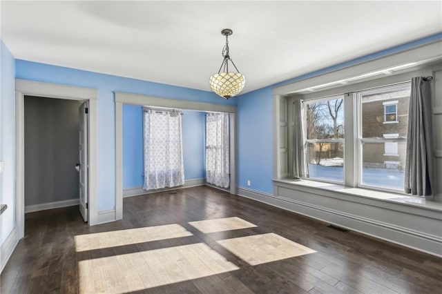 unfurnished room featuring dark hardwood / wood-style flooring and a notable chandelier