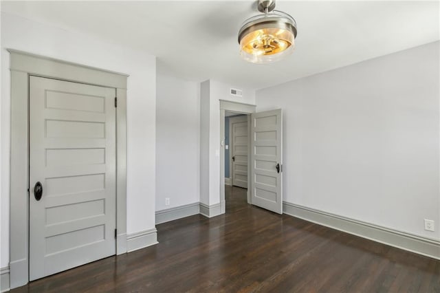 unfurnished bedroom featuring a closet and dark wood-type flooring