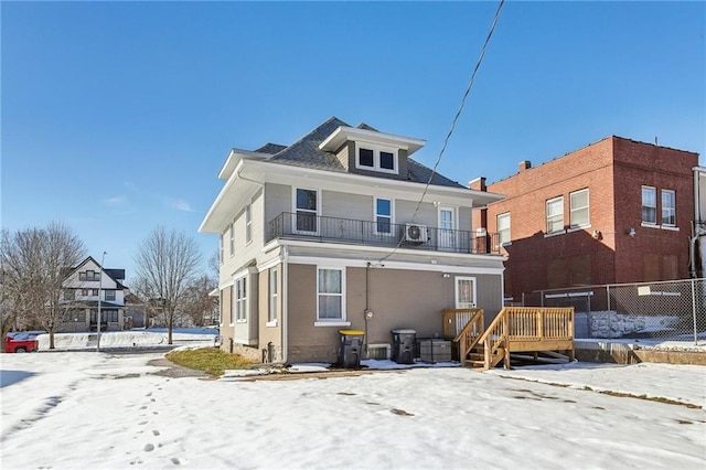 snow covered property featuring cooling unit and a balcony