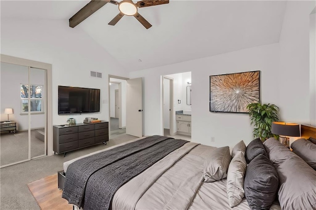 bedroom featuring light carpet, ensuite bathroom, ceiling fan, beamed ceiling, and a closet