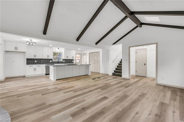 unfurnished living room featuring beamed ceiling, high vaulted ceiling, and light hardwood / wood-style flooring