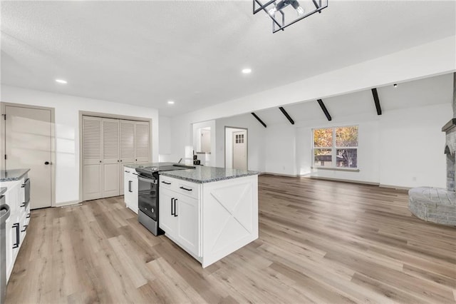 kitchen featuring a center island, stainless steel electric stove, dark stone countertops, light wood-type flooring, and white cabinetry