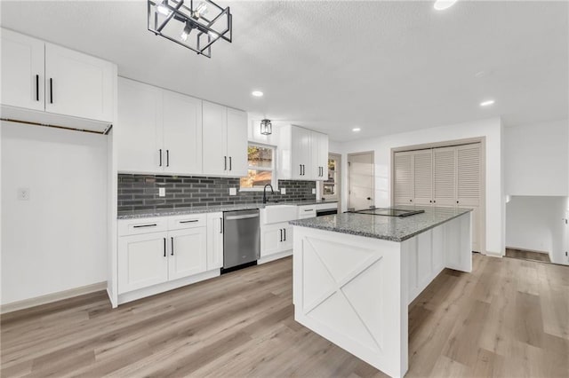 kitchen featuring white cabinets, light wood-type flooring, stone countertops, and stainless steel dishwasher