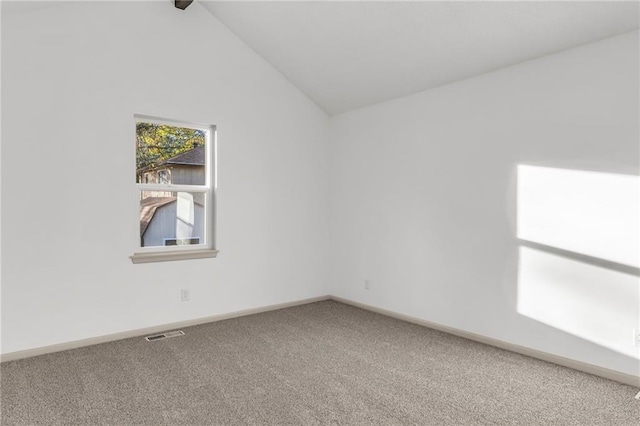 carpeted empty room featuring vaulted ceiling