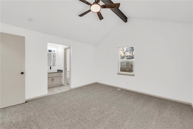 unfurnished bedroom featuring beam ceiling, ceiling fan, high vaulted ceiling, ensuite bathroom, and light carpet