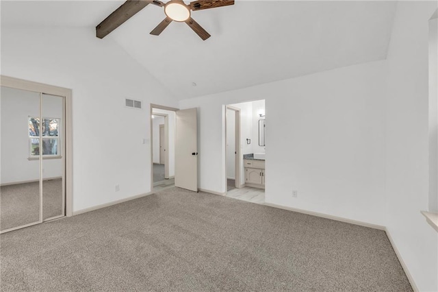 unfurnished bedroom featuring ensuite bath, light colored carpet, ceiling fan, beam ceiling, and a closet