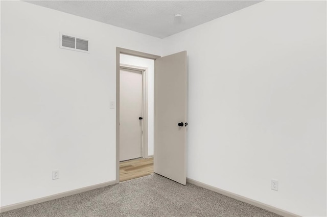 unfurnished room with light carpet and a textured ceiling