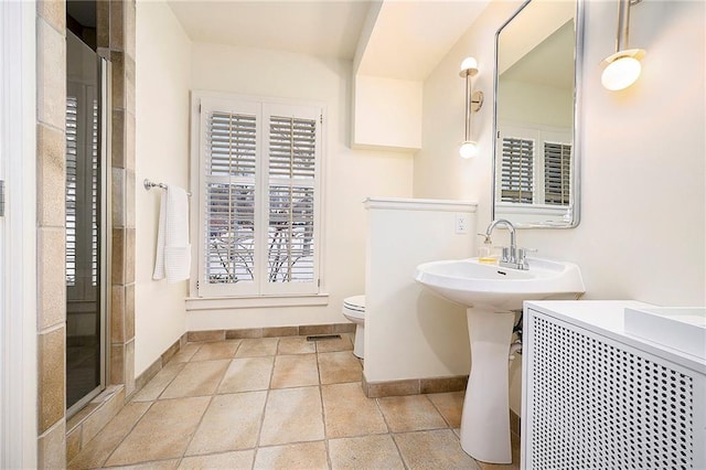 bathroom with sink, a shower with shower door, and toilet