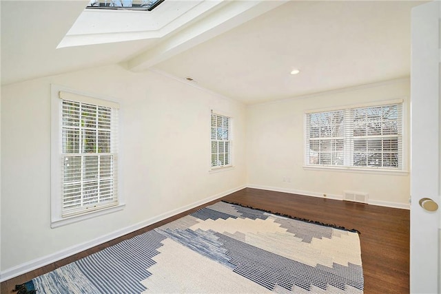 spare room featuring dark hardwood / wood-style flooring and vaulted ceiling with skylight