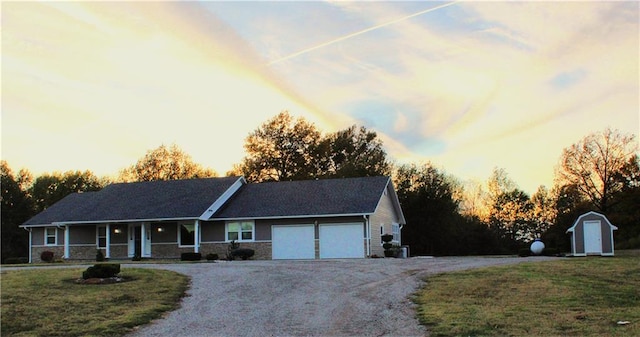 single story home featuring a porch, a garage, a lawn, and a storage unit