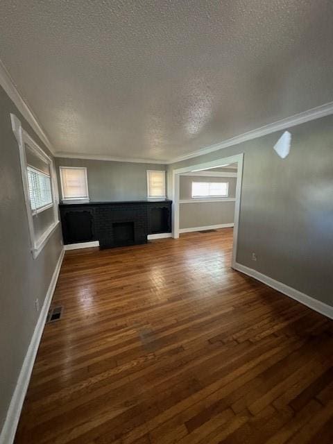 unfurnished living room with crown molding, a textured ceiling, and dark wood-type flooring