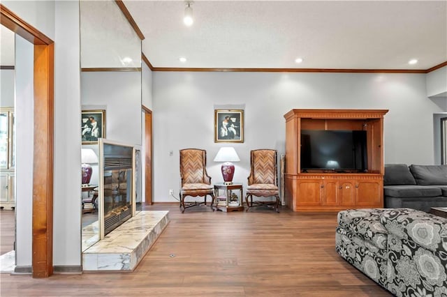 living room featuring wood-type flooring, crown molding, and a tiled fireplace