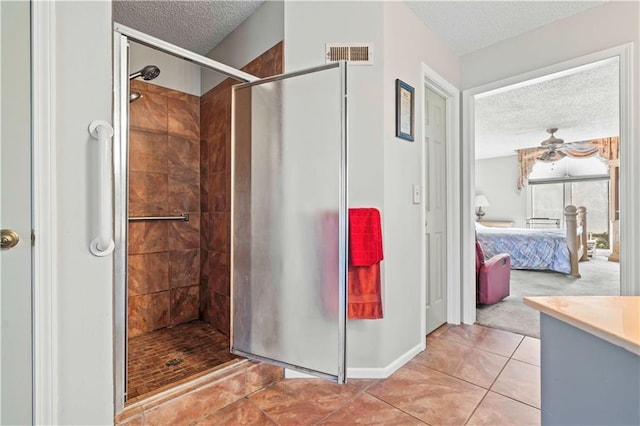 bathroom featuring tile patterned floors, ceiling fan, a tile shower, and a textured ceiling