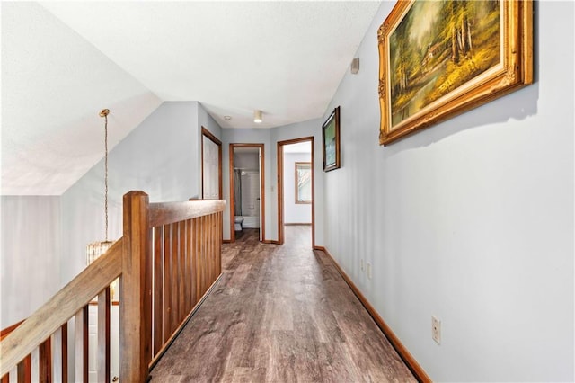 corridor featuring a chandelier, vaulted ceiling, and hardwood / wood-style flooring