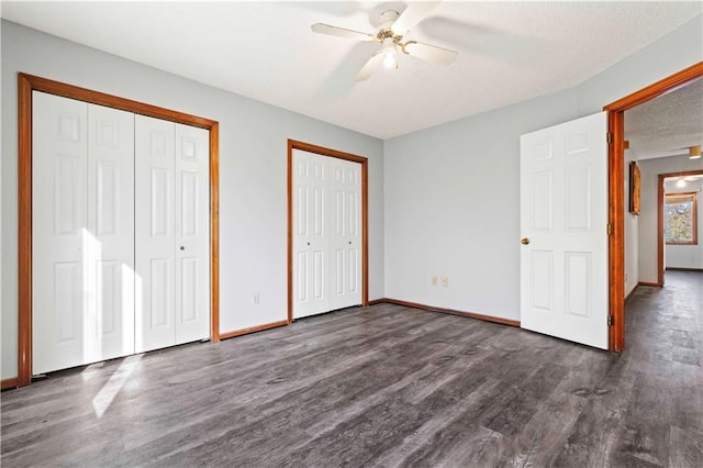 unfurnished bedroom featuring a textured ceiling, two closets, ceiling fan, and dark hardwood / wood-style floors