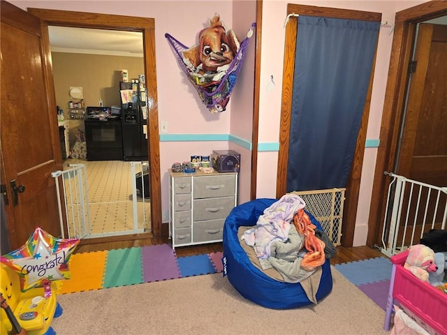 carpeted bedroom with black refrigerator and ornamental molding