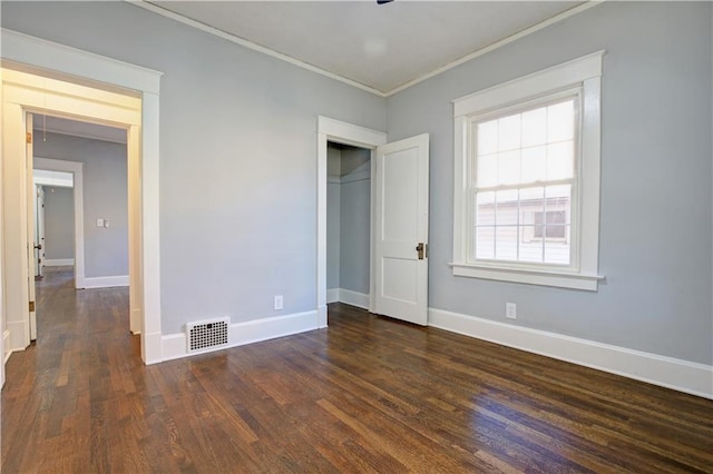 unfurnished bedroom with dark hardwood / wood-style floors, crown molding, and a closet