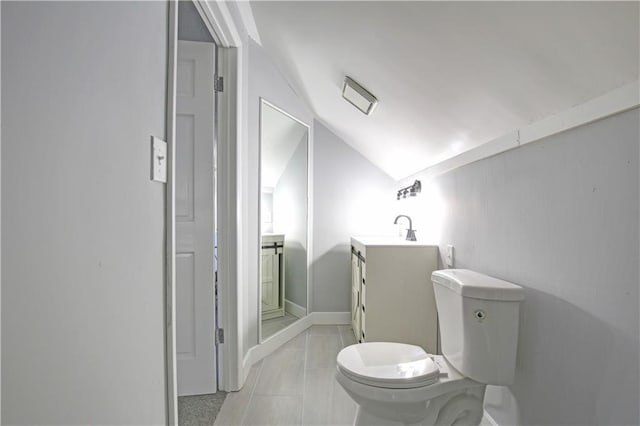 bathroom featuring tile patterned flooring, vanity, vaulted ceiling, and toilet