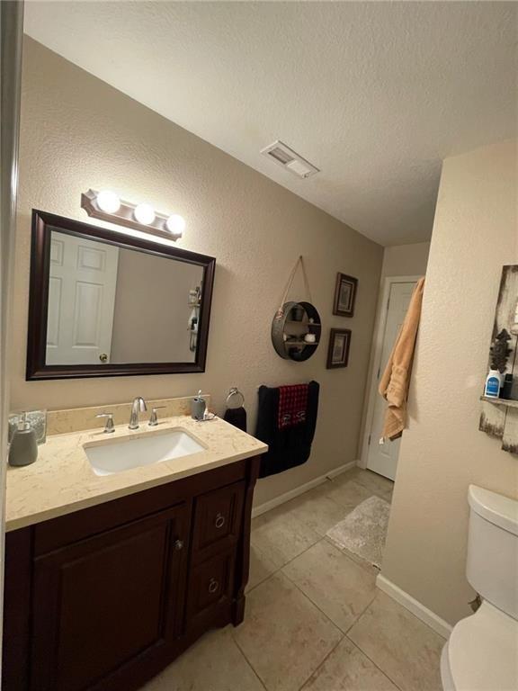 bathroom with tile patterned floors, vanity, toilet, and a textured ceiling