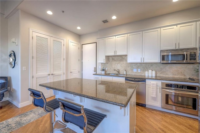 kitchen with appliances with stainless steel finishes, tasteful backsplash, white cabinetry, and a breakfast bar area