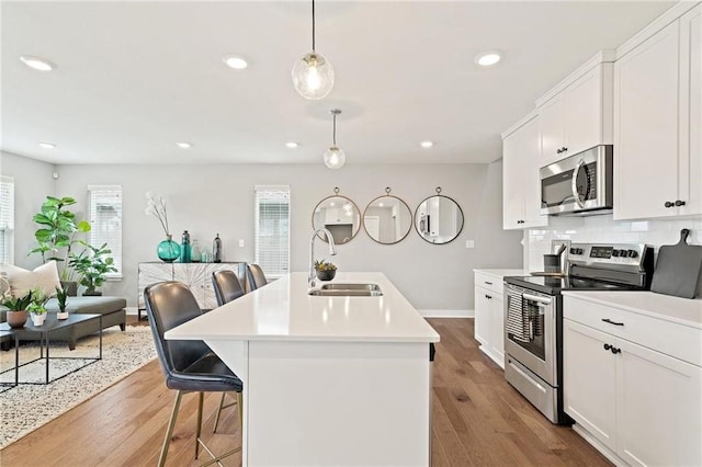 kitchen featuring stainless steel appliances, sink, pendant lighting, a breakfast bar area, and an island with sink