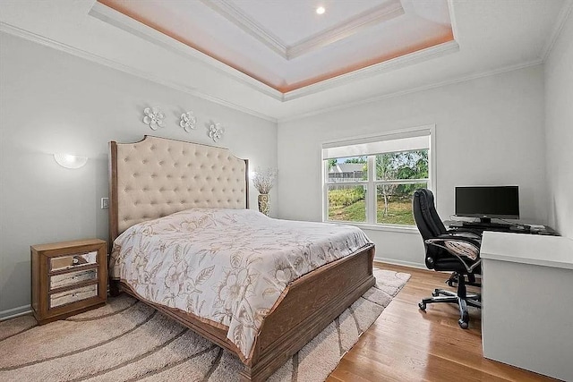 bedroom featuring a raised ceiling, ornamental molding, and light hardwood / wood-style flooring