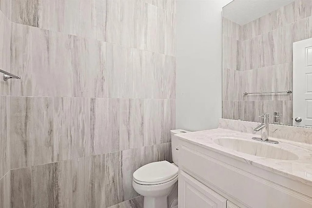 bathroom with vanity, tile walls, and toilet