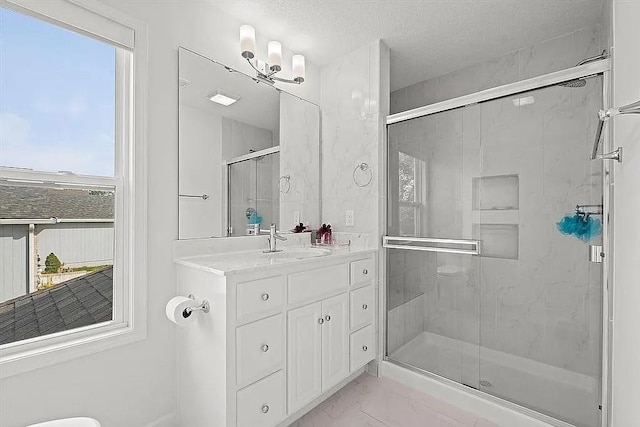 bathroom featuring a textured ceiling, vanity, a healthy amount of sunlight, and a shower with shower door