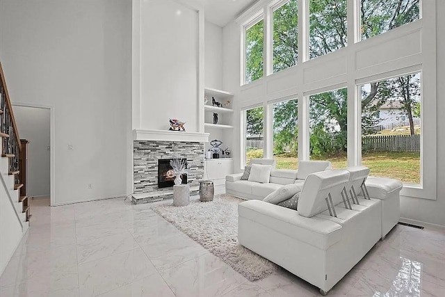 living area with stairs, a healthy amount of sunlight, and marble finish floor