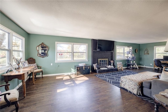 living room featuring a wealth of natural light, dark hardwood / wood-style flooring, a textured ceiling, and a brick fireplace