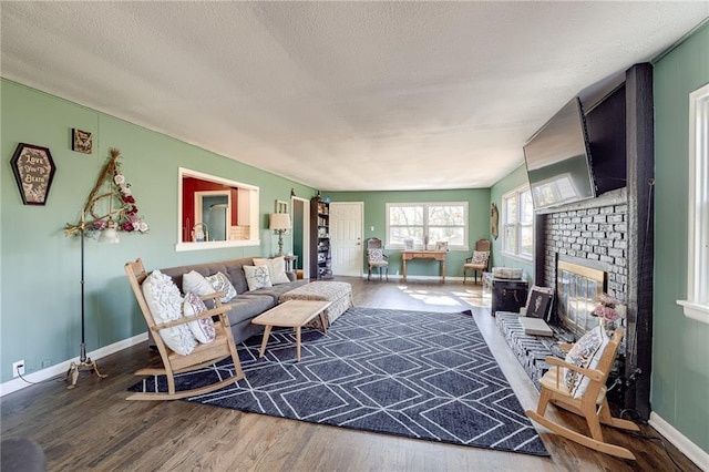 living room featuring hardwood / wood-style flooring, vaulted ceiling, a textured ceiling, and a brick fireplace