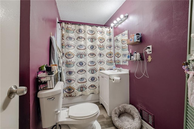 bathroom with a textured ceiling, vanity, and toilet