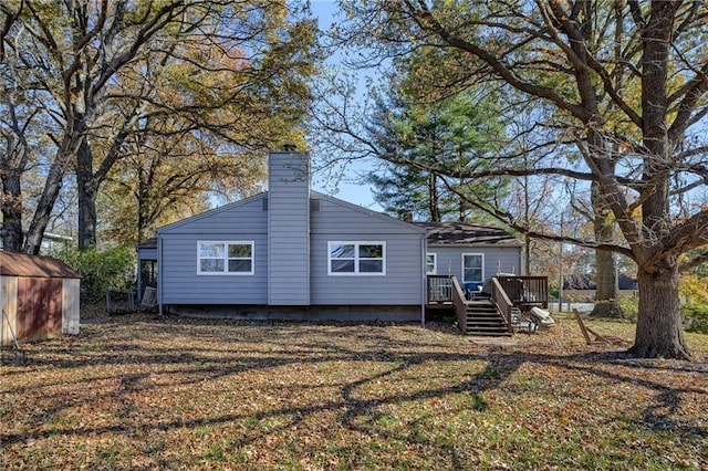 back of property with a wooden deck and a storage unit