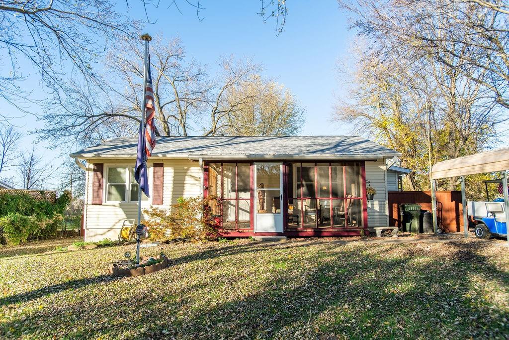 rear view of house featuring a lawn and a sunroom