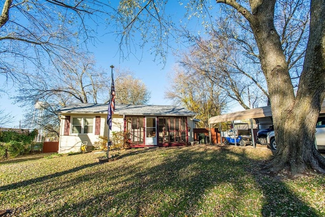 back of property featuring a carport, a sunroom, and a yard