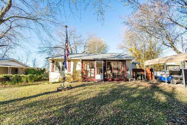 rear view of house with a carport, a sunroom, and a yard