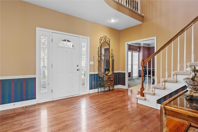 foyer featuring visible vents, wainscoting, wood finished floors, stairs, and recessed lighting