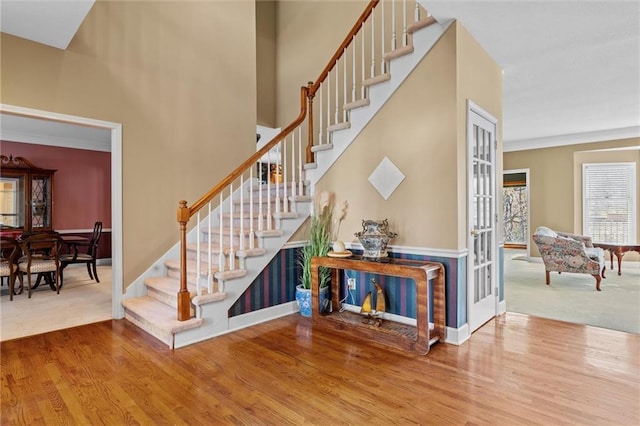 staircase with a high ceiling, baseboards, and wood finished floors