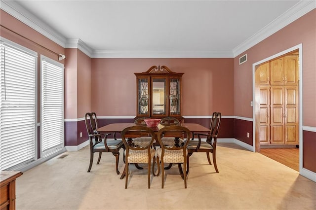 dining space featuring light carpet, baseboards, visible vents, and crown molding