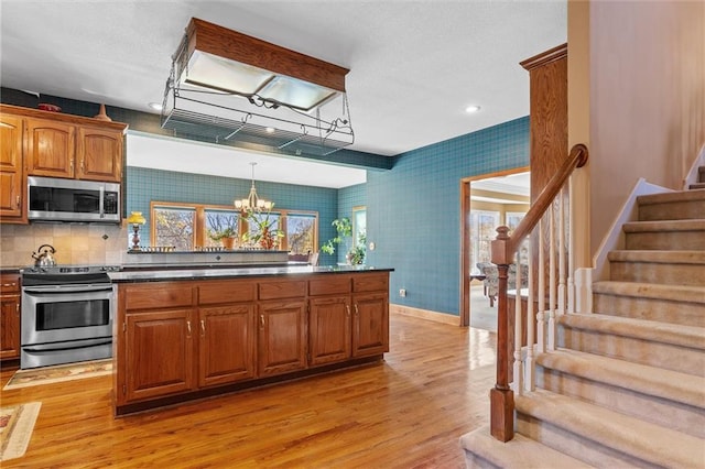 kitchen with a chandelier, appliances with stainless steel finishes, light hardwood / wood-style floors, and hanging light fixtures