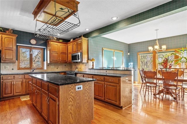 kitchen featuring a peninsula, stainless steel microwave, a kitchen island, and wallpapered walls