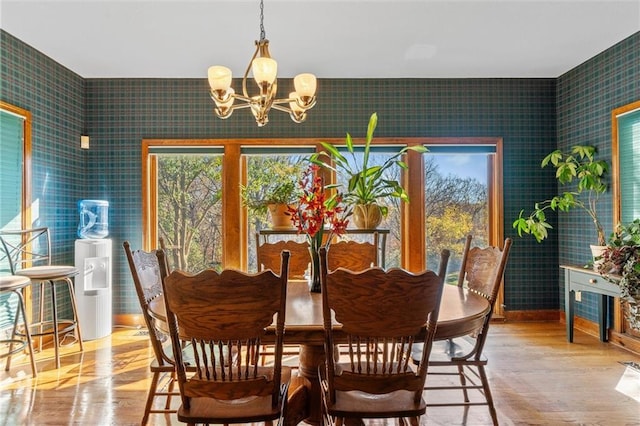 dining area featuring a notable chandelier, wood finished floors, and wallpapered walls