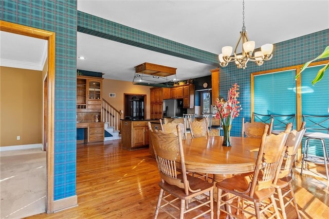 dining room with light wood-type flooring, wallpapered walls, stairs, and baseboards