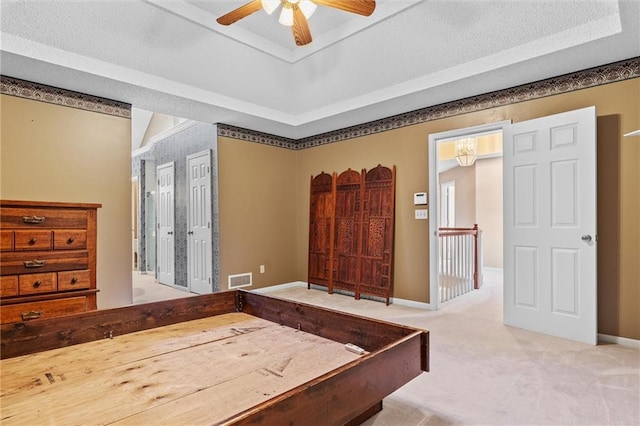 carpeted bedroom with ceiling fan, a raised ceiling, and a textured ceiling