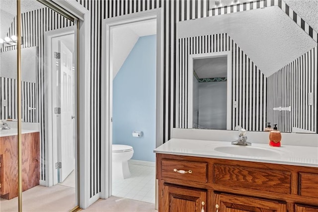 bathroom with tile patterned flooring, a textured ceiling, vanity, and toilet