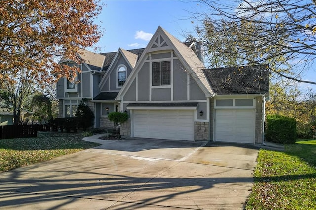 tudor-style house with roof with shingles, concrete driveway, and stucco siding