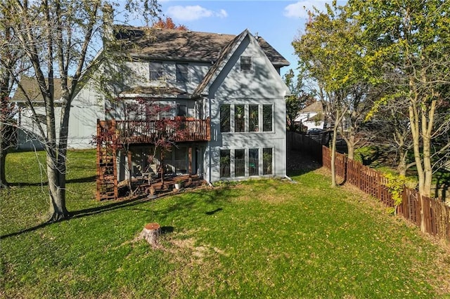 back of property with a deck, a lawn, and a fenced backyard