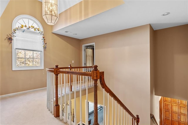 corridor with light colored carpet and a notable chandelier